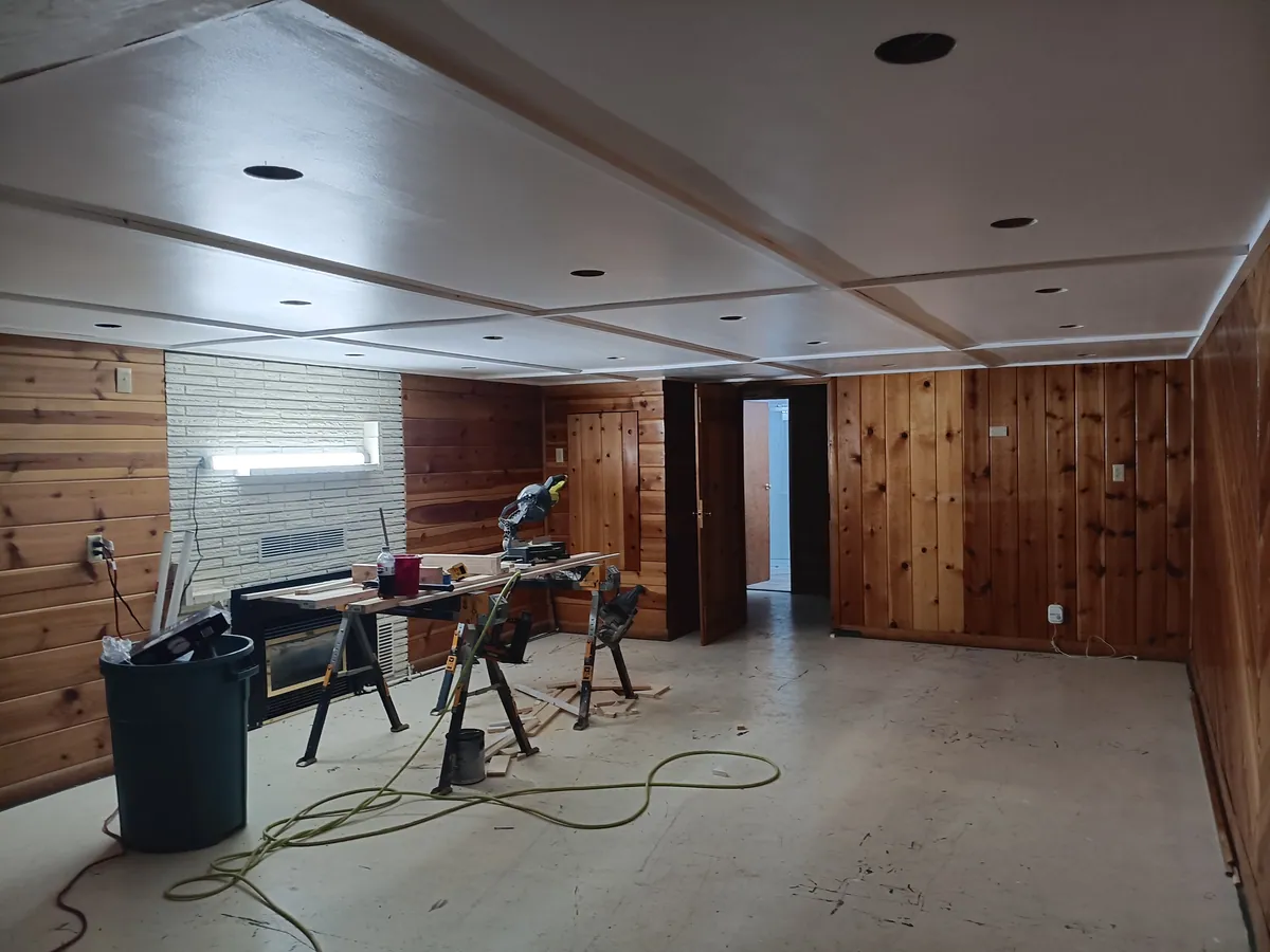 The same basement before coating, with bare grey concrete and tools still on the floor