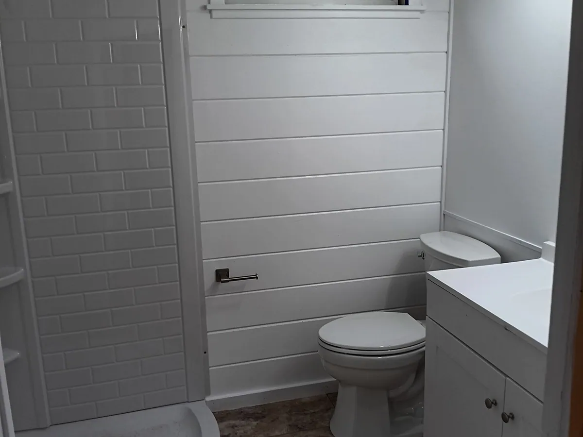 A bathroom we fully remodeled with a new shower base, toilet, vanity and shiplap walls