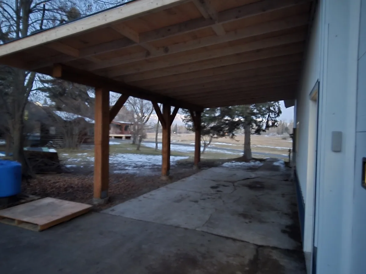 Heavy timber post and beam covered porch with exposed rafters running the length of a building