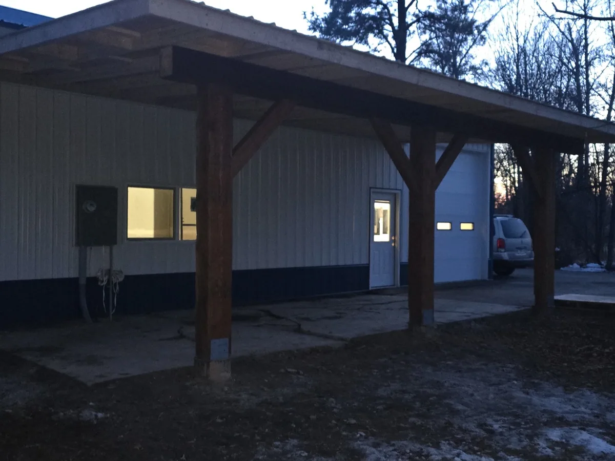 The gable end of a heavy timber covered porch with knee braces and a standing seam roof above